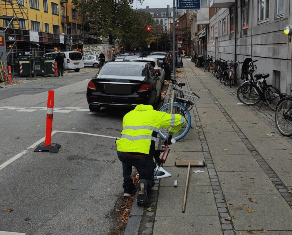 Tekniker installerer parkeringssensor på en gade i København